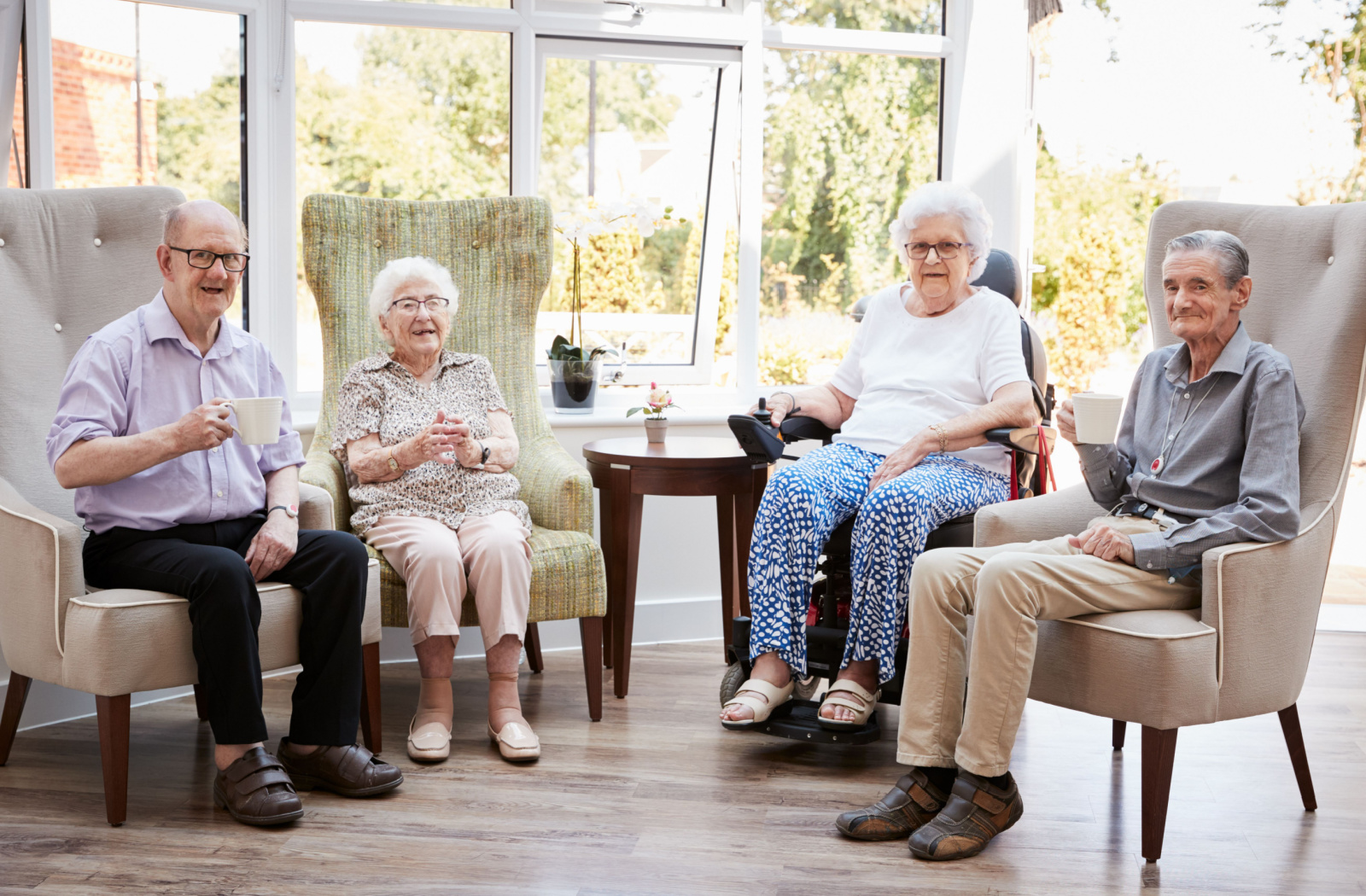 A group of seniors sitting, talking to each other, and having a cup of tea in a senior living community