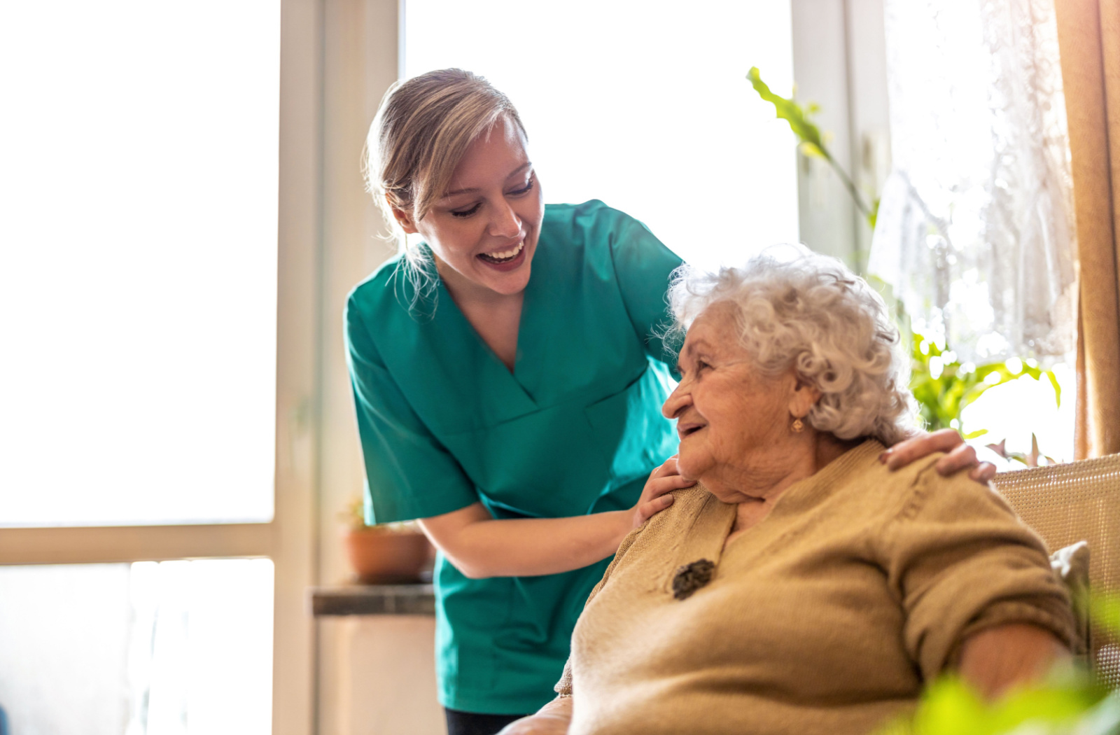 A female caregiver talking to an older adult woman in a hospice care facility