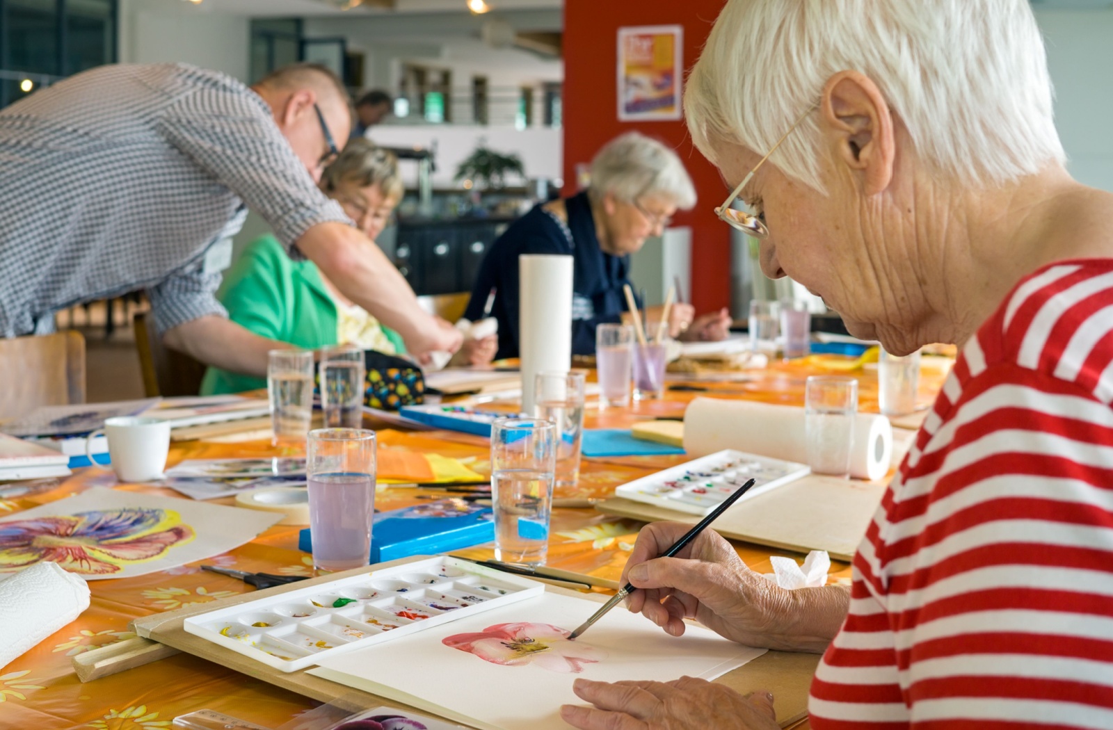 A group of senior women at a table painting with water colors.