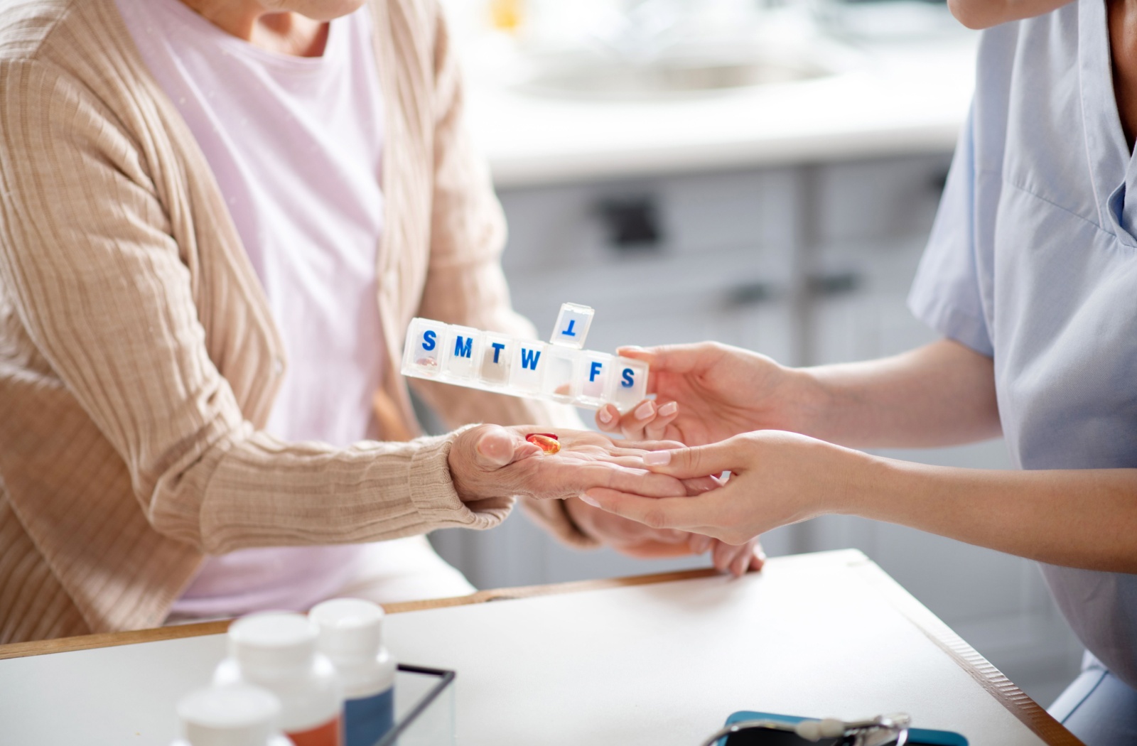 A close up of a nurse putting pills into a senior woman's hand
