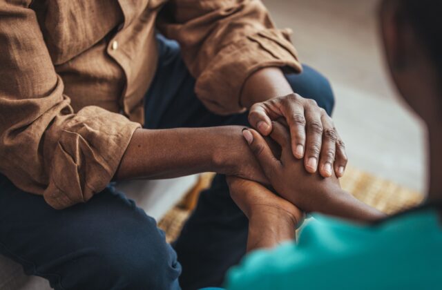 A close up of a family holding hands as they discuss end of life care plans.