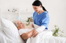 A hospice caregiver assisting an elderly woman get ready for bed.