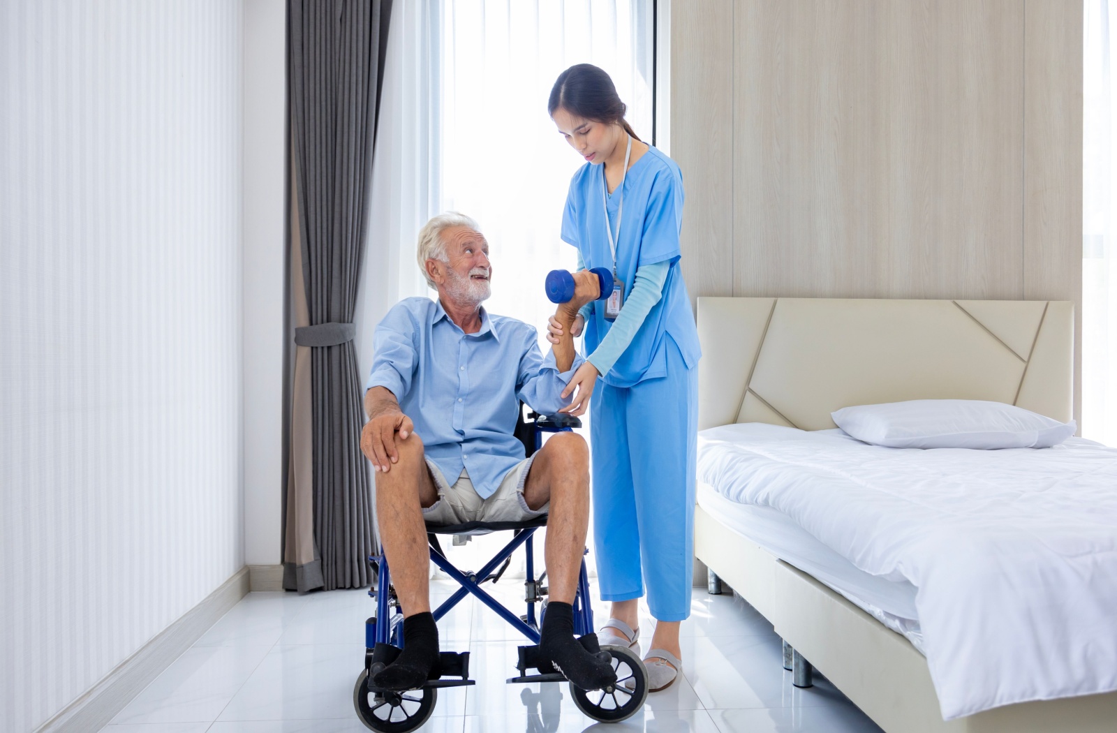 A respite care worker helps an elderly man with light exercise.
