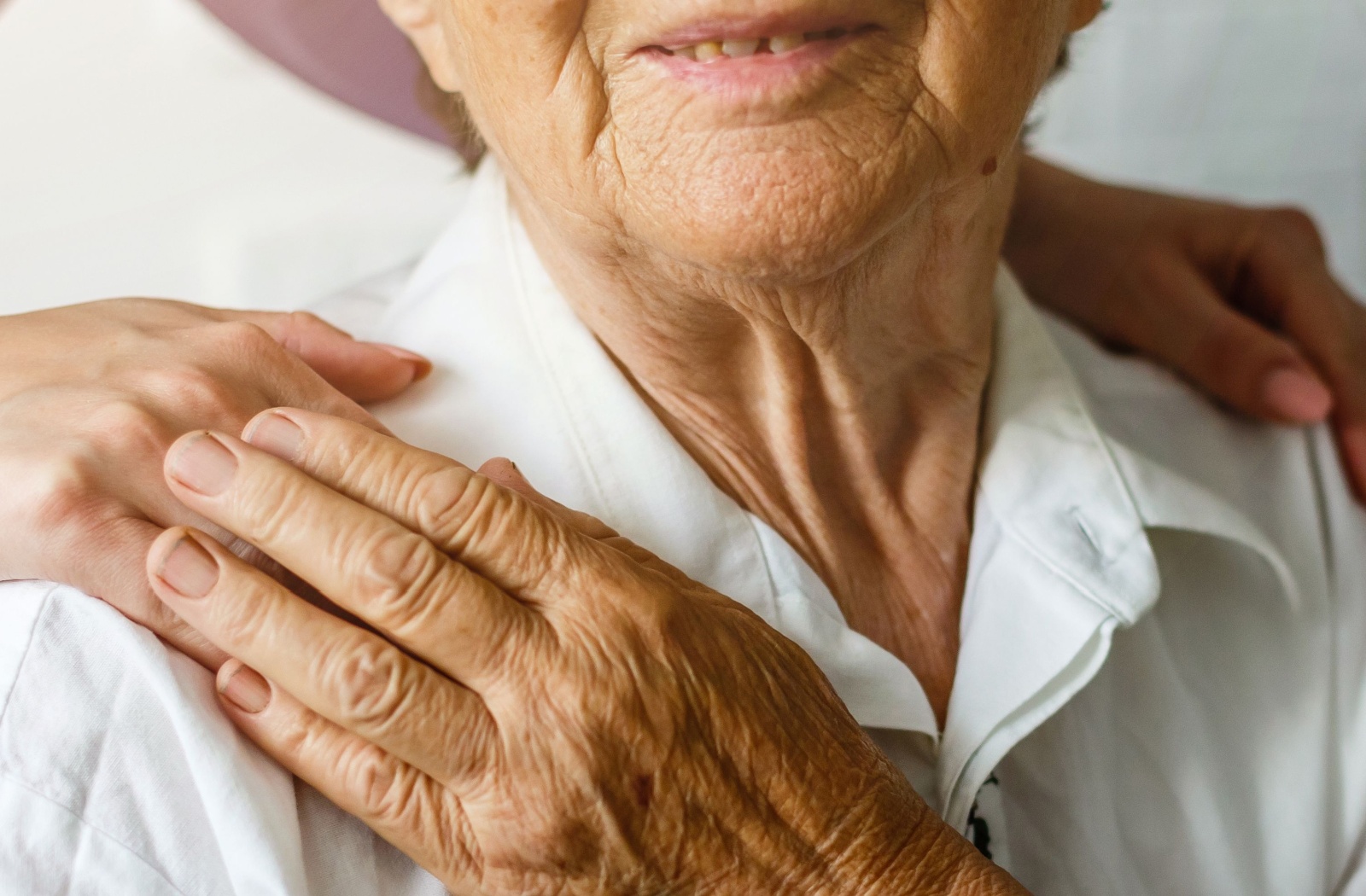 A hospice patient gently touches the hand of their caregiver.